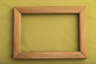 Wooden frame on smooth green olive silk tissue. Top view, flat lay, natural textile background and