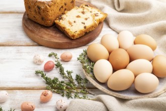 Homemade easter pie with raisins and eggs on plate on a white wooden background and linen textile.