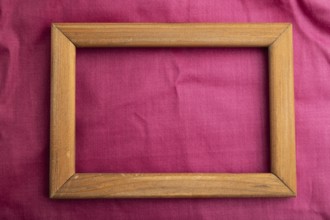 Wooden frame on smooth cotton purple tissue. Top view, flat lay, natural textile background and