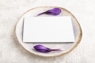 White paper invitation card, mockup with crocus flowers on ceramic plate and gray concrete