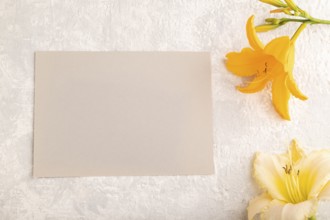 Gray paper business card mockup with orange day-lily flower on gray concrete background. Blank, top