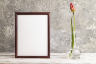 Wooden frame with red tulip flower in glass on gray concrete background. side view, copy space,