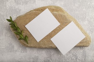 White paper business card, mockup with natural stone and boxwood branch on gray concrete background