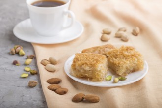 Traditional arabic sweets (basbus, kunafa, baklava) and a cup of coffee on a gray concrete