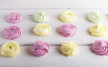 Set of colored meringues on white wooden background. top view, flat lay. geometric pattern