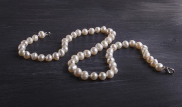 Caramel colored pearl beads on a black background. top view, close up