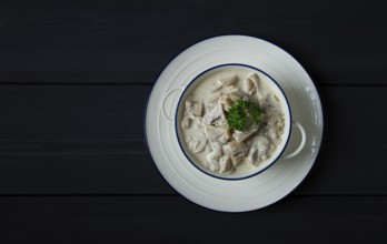 Cream sauce with mushrooms, top view, on a dark gray wooden table, horizontal, no people