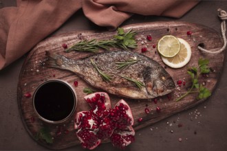 Fried dorado fish, with spices and herbs, on a wooden board, pomegranate sauce, close-up, no people