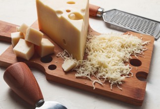 Grated cheese, Maasdam, on a cutting board, grater and cheese knife, close-up, no people