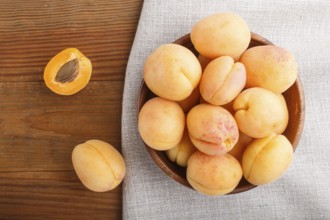 Fresh orange apricots in wooden bowl on wooden background. top view, flat lay, close up