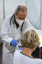 Vaccinator administers a vaccination, during the test run in the vaccination centre for corona