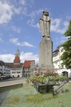 Tausendgüldenbrunnen with column, sculpture and water basin, town hall with church tower of St