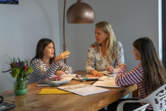 Homeschooling, during the lockdown in January 2021, mother helps her two daughters, at home,