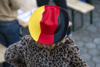 Woman with fur coat and hat in the German national colours black red gold, at a public viewing