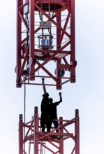 Erection of a construction crane, part of the upper crane section is hoisted by mobile crane onto