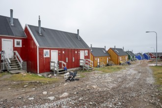 Row of colourful houses along a gravel road under a cloudy sky, remote Arctic Inuit settlement