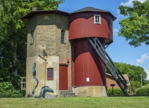 Historic pump house for filling up water on steam locomotives. In the foreground a statue of a