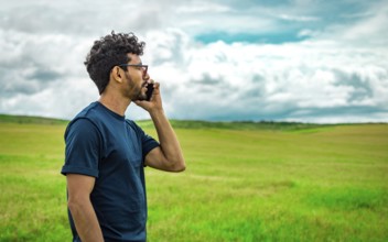 Man on the road talking on the phone. Young man talking on the phone in the field