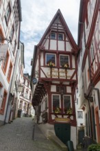 Half-timbered house in a narrow old town street with floral decorations and romantic atmosphere,