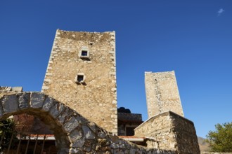 Stone towers of an ancient structure with an arch and blue sky in the background, Flomochori,