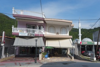 A two-storey building with a shop on the ground floor and a small minaret next to it, Typical