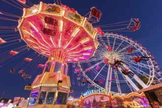 Illuminated carousel and Ferris wheel at night in a lively amusement park, funfair, wave flight,