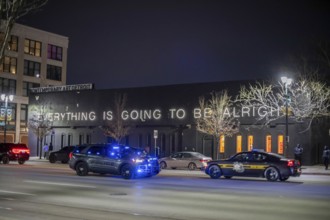 Detroit, Michigan - Police cars pass a sign reading 'Everything is Going to be Alright' at the