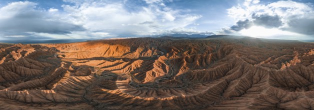 Panorama, landscape of eroded hills at Lake Issyk Kul, badlands at sunset, mountain peaks of the