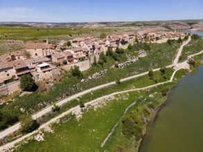 A riverside village with roads crossing the green surroundings and running alongside the houses,