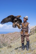 Traditional Kyrgyz eagle hunter with eagle in the mountains, near Kysyl-Suu, Kyrgyzstan, Asia