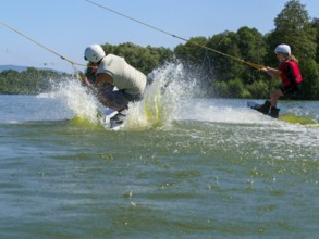 Children go wakeboarding together on the lake, water sports, water skiing and wake park