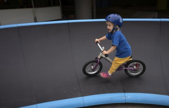 Little girl, 3 years, blonde, helmet, helmet, riding on balance bike, bicycle, skating rink,