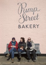 People sitting outside on sunny winter day Pump Street bakery, Orford, Suffolk, England, UK