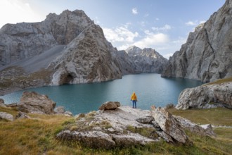 Tourist at the blue mountain lake between rocky steep mountain peaks, Kol Suu Lake, Sary Beles