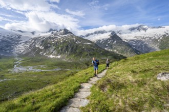 Two mountaineers on hiking trail in picturesque mountain landscape, mountain peak with snow and