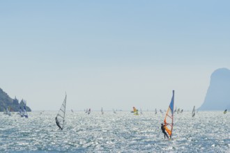 People windsurfing on a sunny day with clear blue skies and mountain backdrop, Lake garda, Torbole,