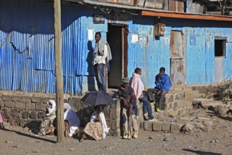 Europia district, locals waiting in front of a blue corrugated iron hut, Ethiopia, Africa