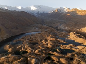 White glaciated and snowy mountain peak Pik Lenin at sunrise, hilly landscape with golden yellow