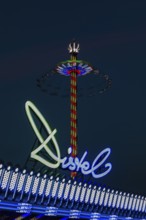 Illuminated lettering Distel, behind the illuminated Bayern Tower in motion, night shot,