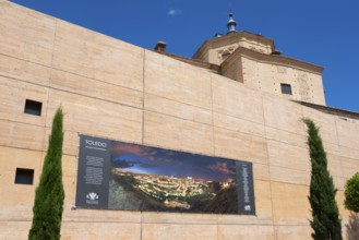 Large stone building with information panel about Toledo on a sunny wall, archive, urban