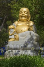 Golden Buddha statue, surrounded by flowers and green nature, radiates peace and spirituality under