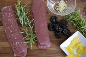 Swabian cuisine, preparation of lamb with prunes, raw lamb, rosemary, herbs, sliced garlic, lemon