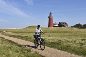 Woman with bicycle at Bovbjerg lighthouse in Denmark