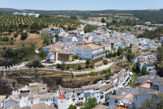 Panoramic view over a village with olive groves and white buildings on hillsides, cave dwellings,