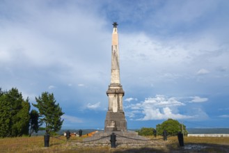 Sublime stone obelisk monument in an open field under a dramatic sky, commemorating the