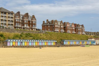 Colourful beach huts and historic clifftop buildings, South Beach, Lowestoft, Suffolk, England, UK