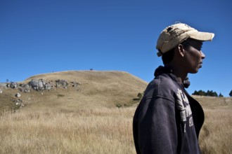 Portrait of a young man belonging to the Betsileo ethnic group. In the background, a sacred hill is