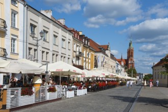 Lively street with historic houses and church tower in a summer atmosphere, Kosciuszko market