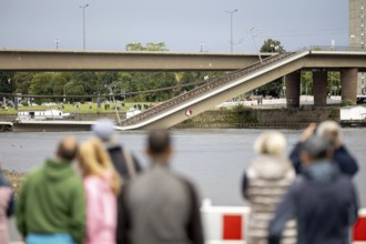 Passers-by look at the partially collapsed Carola Bridge from the Königsufer in Dresden, 11/09/2024