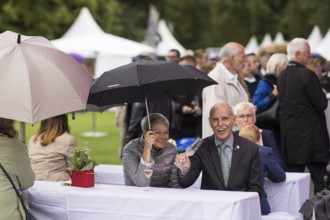 Guests under umbrellas at the Federal President's citizens' festival in Bellevue Palace Gardens,